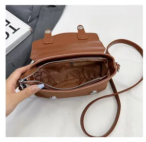 Detail of brown PU leather crossbody bag interior showing main pocket and zipper pocket