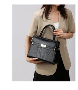 Detail of black faux leather tote with snakeskin texture and golden turn-lock closure