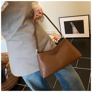 Detail of vintage brown crocodile embossed bag featuring a woven strap and silver metal buckle