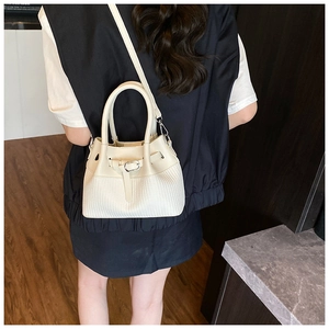 Détail du sac à bandoulière beige avec texture matelassée et boucle argentée porté