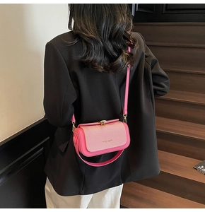 Rosa quadratische Handtasche mit Metallschnalle und Trageriemen am Model auf Holztreppen