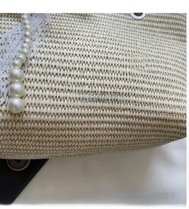 Detail of woven straw bag showing lace trim, pearl beads, and fashion leather logo