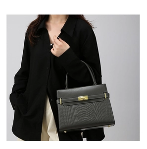 Detail of grey trapezoid handbag with snakeskin embossed texture and gold twist lock