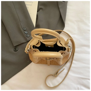 Détail du sac seau en paille tissée avec garniture en cuir kaki et bandoulière réglable