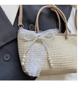 Detail of straw bag featuring a large white lace bow and elegant faux pearl charms