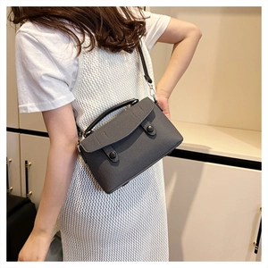 Detail of dark grey woven texture handbag with round clasp and crossbody strap