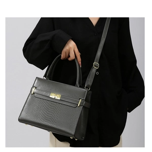 Detail of dark gray snakeskin embossed handbag with gold twist lock and woven strap
