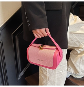 Detail der rosa Webstruktur und des goldenen Muschelschlosses an der Handtasche
