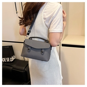 Detail view of the adjustable black leather strap and buckle on the dark grey messenger bag