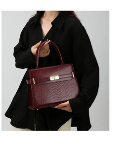 Detail view of wine red shoulder bag with crocodile texture and gold clasp