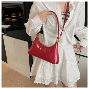 Detailed view of red crescent shoulder bag with glossy finish and gold-tone hardware