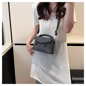 Detail of dark grey textured crossbody bag with black buckle closures and strap