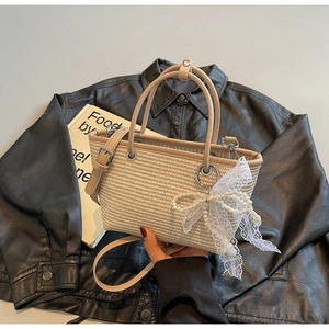 Detail of straw woven tote with bow pearl charm and cream leather straps
