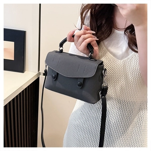 Detail of grey textured fabric messenger bag with top handle and black shoulder strap
