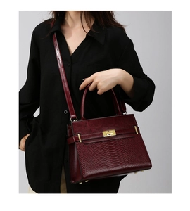 Detail view of burgundy leather handbag with crocodile pattern texture and gold metal buckle