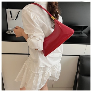 Red high-gloss patent leather shoulder bag with sleek minimalist design and gold hardware