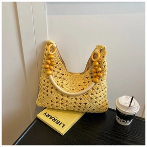 Détail d'un sac cabas en crochet jaune avec texture florale et anse en perles de bois chic