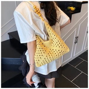 Détail du sac en tricot jaune évidé avec bandoulière en perles de bois sur modèle