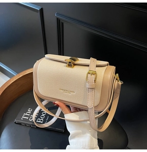 Detail der braunen Ledertasche mit beigem Webmuster und goldenem Muschelverschluss
