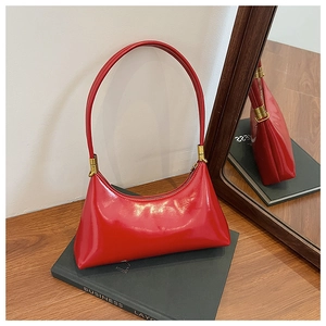 Detail of red patent leather crescent bag with gold zipper on a professional book