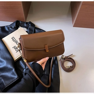 Détail du sac bandoulière en cuir marron avec boucle dorée et deux types de lanières