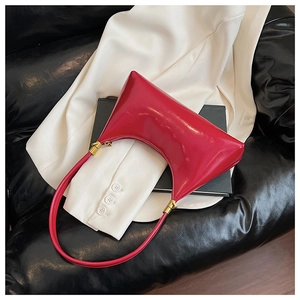 Detail of red crescent shoulder bag with glossy patent leather finish and gold zipper