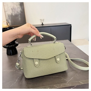 Detail of light green twill fabric handbag with top handle and adjustable strap