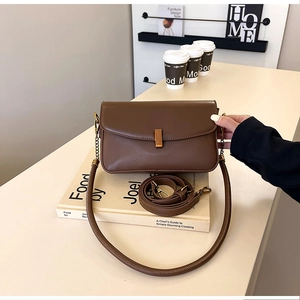 Détail d'un sac en cuir marron foncé avec fermoir doré et doubles bandoulières