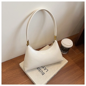 Detail view of cream hobo bag with gold hardware placed on books with a coffee cup