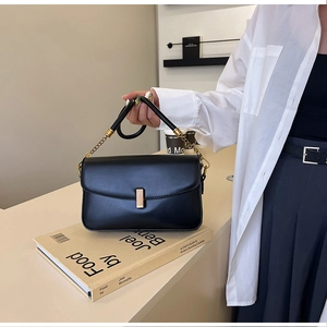 Détail du sac bandoulière en cuir noir avec boucle métallique dorée et chaîne
