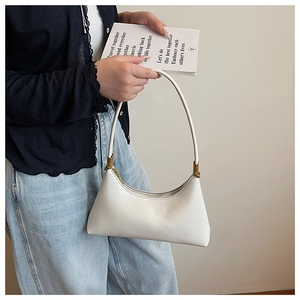 Close-up of a white leather crescent shoulder bag with elegant gold metal hardware detail