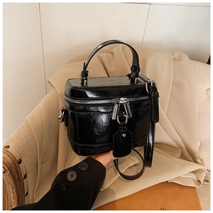 Detailaufnahme der glänzenden schwarzen Box-Tasche mit silbernen Metallteilen und Griff