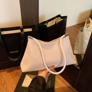 Pink woven half-moon shoulder bag with minimalist braided pattern and silver hardware