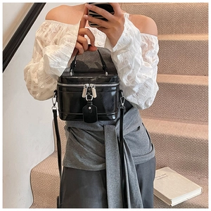 Detail einer schwarzen Glanz-Box-Tasche mit Silberbeschlägen, präsentiert an einer Treppe