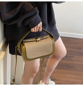 Detailansicht der olivgrünen Umhängetasche aus Canvas und Leder, von einem Model gehalten