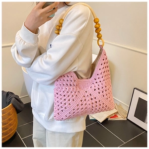 Détail d'un sac à bandoulière en crochet rose avec anse unique en perles de bois naturel
