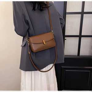 Détail du sac bandoulière marron avec boucle en métal doré et bandoulière en cuir