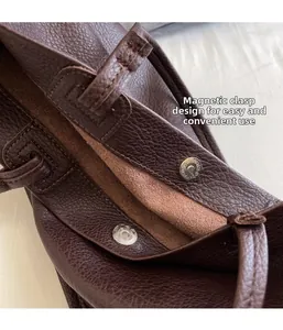Close-up detail of the secure magnetic clasp on textured dark brown leather tote bag