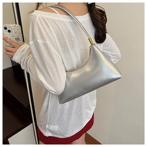 Detail view of silver crescent shoulder bag with metallic finish and gold hardware accents
