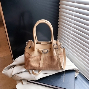 Sac à main chic en cuir beige et paille avec bandoulière sur une veste blanche