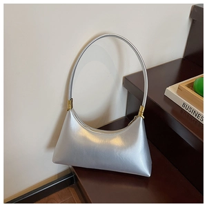 Detail of silver crescent shoulder bag with metallic finish and gold hardware accents