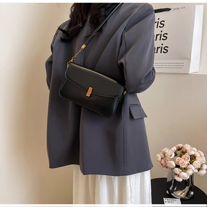 Vue détaillée d'un sac bandoulière en cuir noir avec une boucle métallique dorée minimaliste