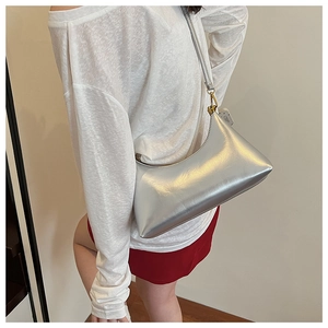 Detail of silver crescent shoulder bag featuring metallic finish and slim strap design