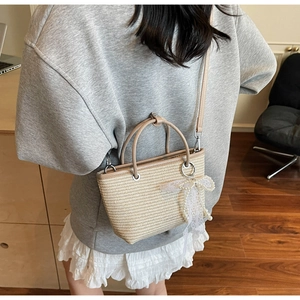 Detail of hand-woven straw bag with elegant lace bow and pearl charm for women