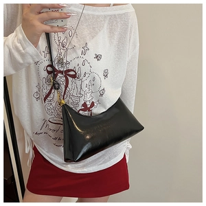 Detail of a black glossy leather crescent hobo bag with vintage gold hardware and strap