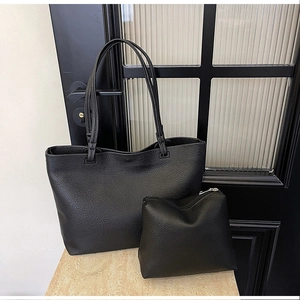 Detail of black large capacity tote bag and matching pouch on marble surface