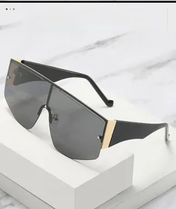 Detail of oversized shield sunglasses with gold metal hinge and wide black temples