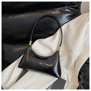 Close-up of black glossy crescent bag with golden cylindrical metal buckle and sleek leather