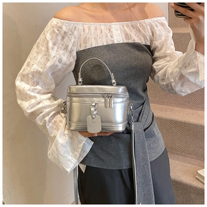 Detailansicht einer silbernen Metall-Box-Tasche mit Doppel-Reißverschluss und Griff