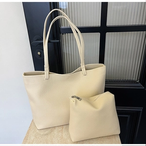 Detail of beige tote bag set featuring pebbled leather texture and matching small pouch